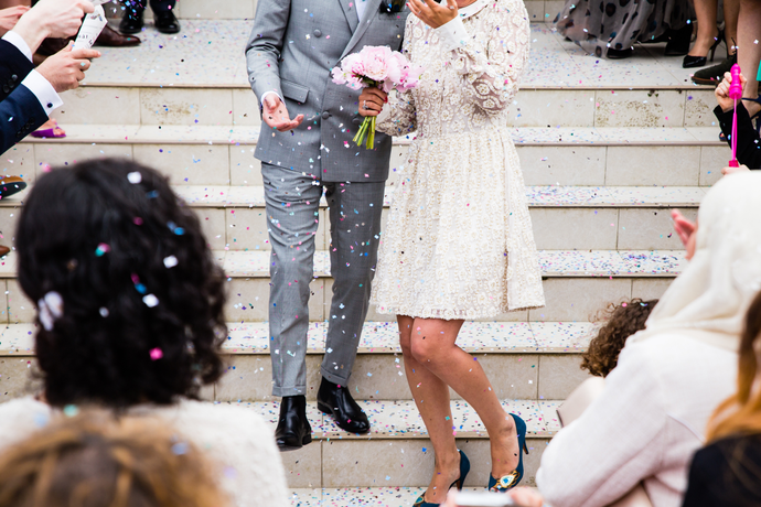 Just married couple walking down a set of stairs having confetti thrown at them