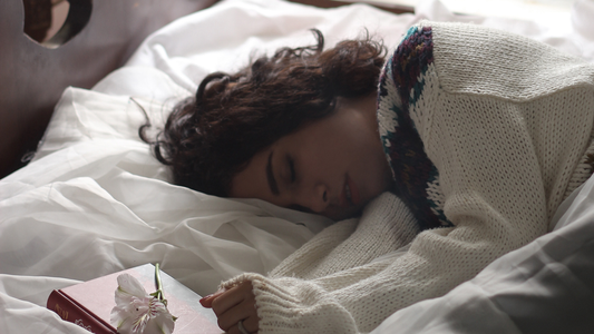 Woman sleeping on her side with a book in her hand