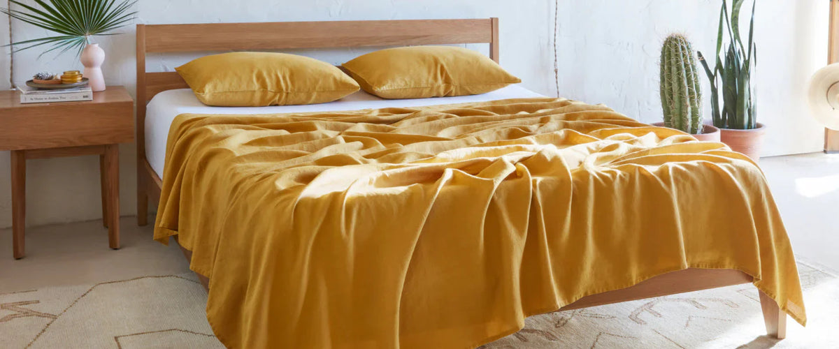 Brown bed frame hoisting a white mattress with a gold comforter that was  messing on the bed.  There were 2 pillows within 2 gold pillowcases.