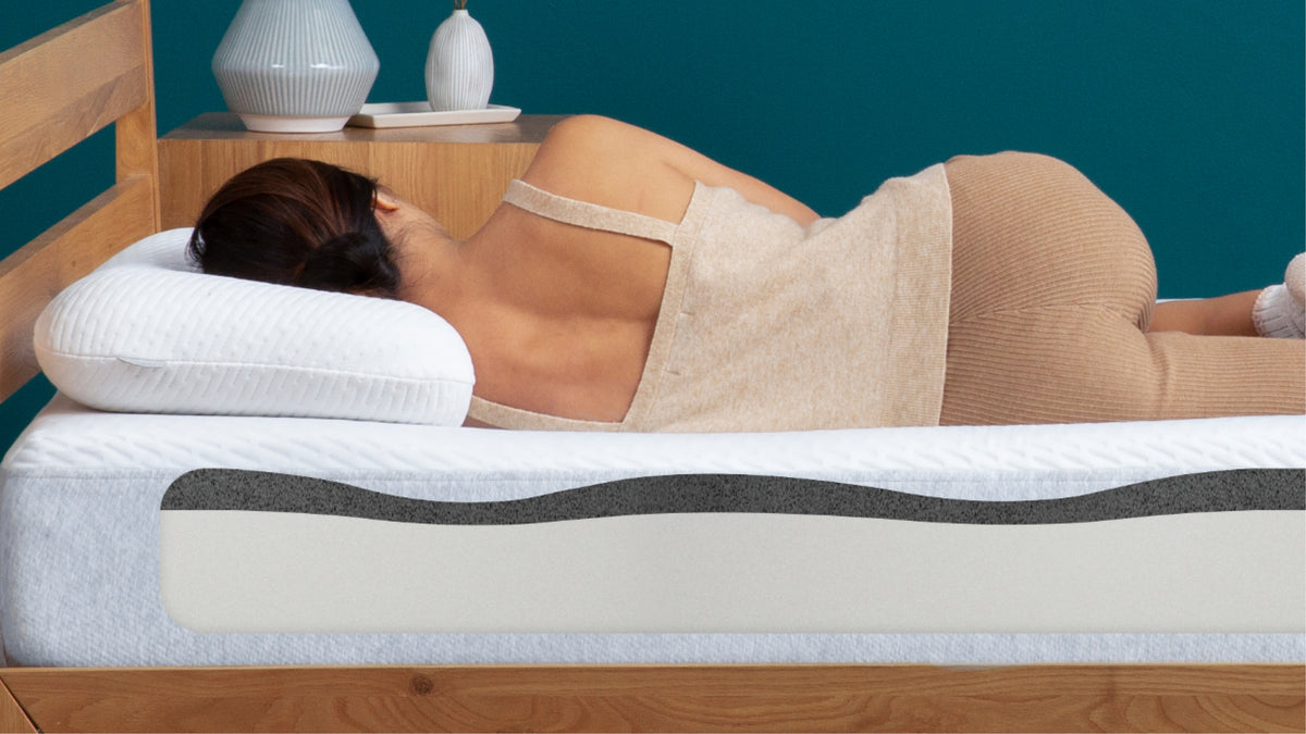 Person lying on a mattress with a剖面 view showing its layers, in a bedroom setting.