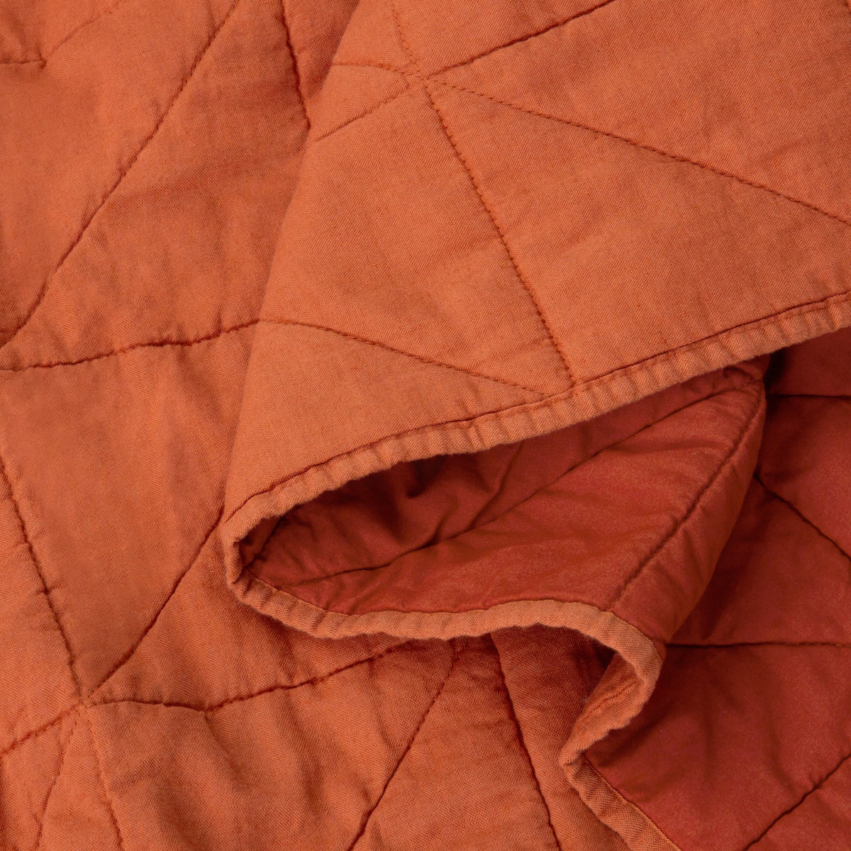 Close-up view of the fabric on the Tuft and Needle Quilt color cayenne