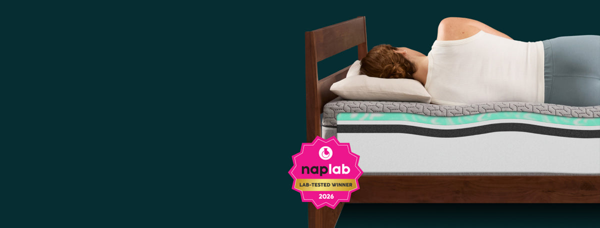 Woman laying on a Tuft and Needle mattress showcasing a naplab award badge.