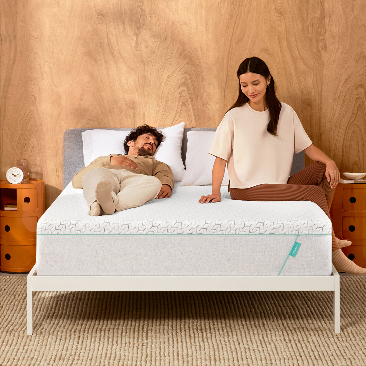 Man and woman laying on a Tuft & Needle Original Hybrid mattress sitting in a white bedframe