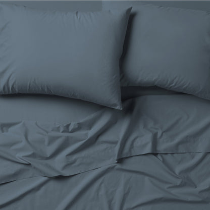 The Tuft and Needle Classic Percale Pillowcase Set, 2 pillows in a pillowcase on top of a spread out sheet || color: Slate
