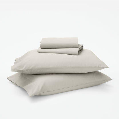 The Tuft and Needle Classic Percale Sheet Set, 1 sheet and pillowcases stacked on top of 2 pillows || color: Sand