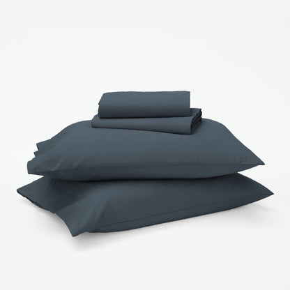The Tuft and Needle Classic Percale Sheet Set, 1 sheet and pillowcases stacked on top of 2 pillows || color: Slate