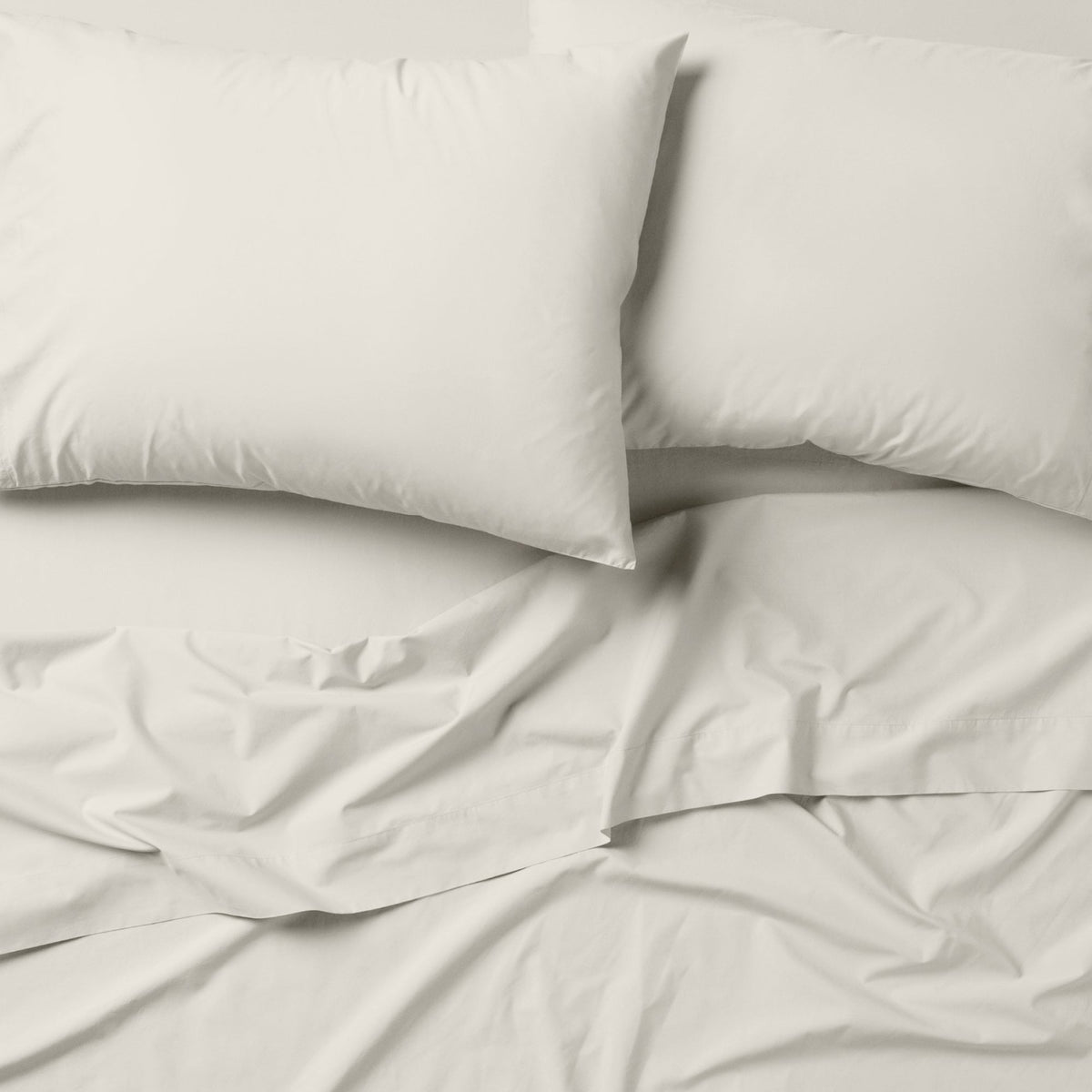 The Tuft and Needle Classic Percale Sheet Set, 2 pillows on top of a sheet on a mattress || color: Sage
