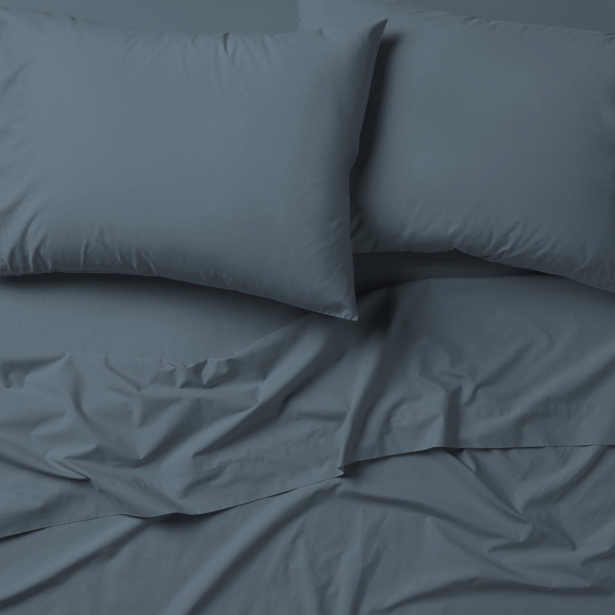 The Tuft and Needle Classic Percale Sheet Set, 2 pillows on top of a sheet on a mattress || color: Slate
