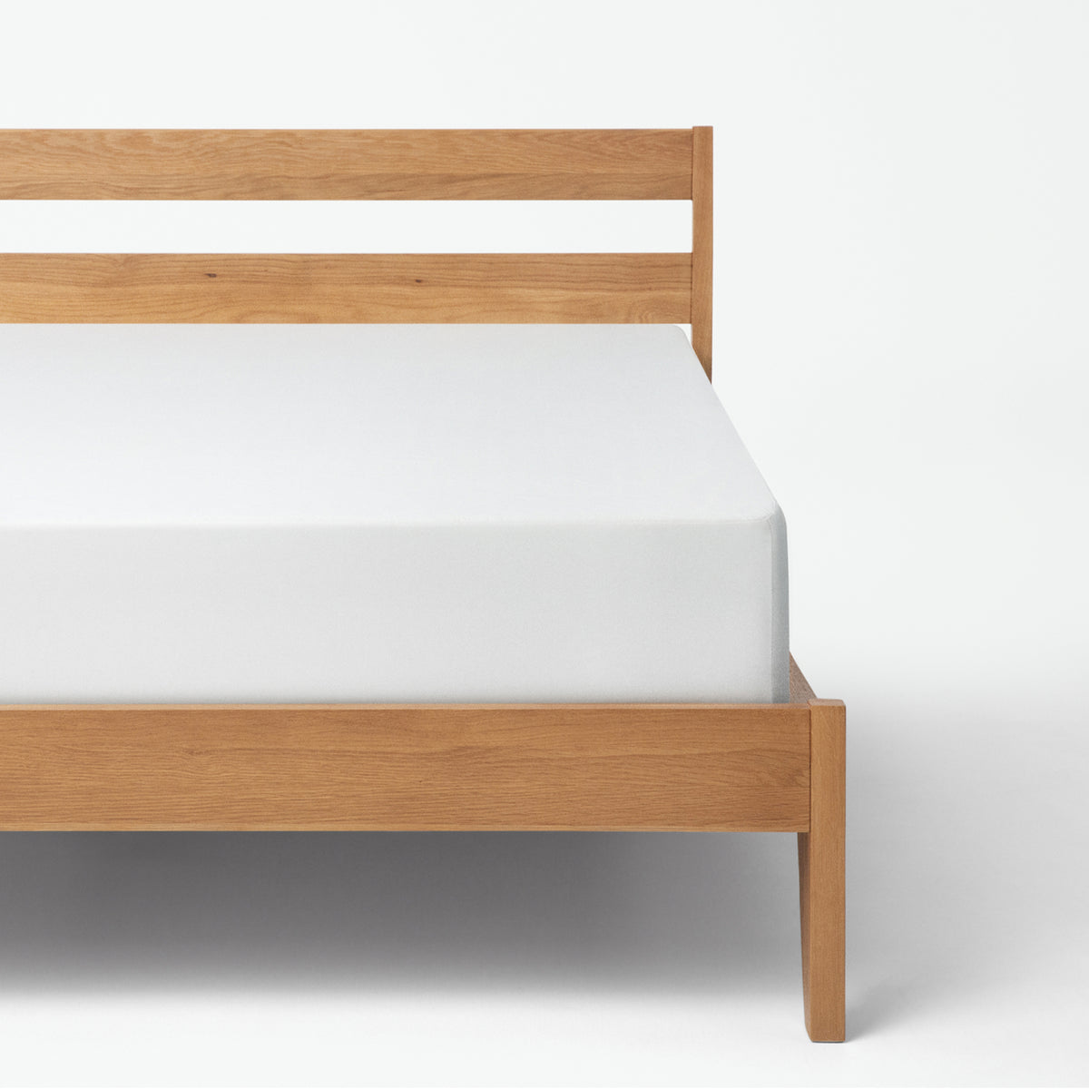Tuft & Needle Wooden bed frame with white mattress on a white background