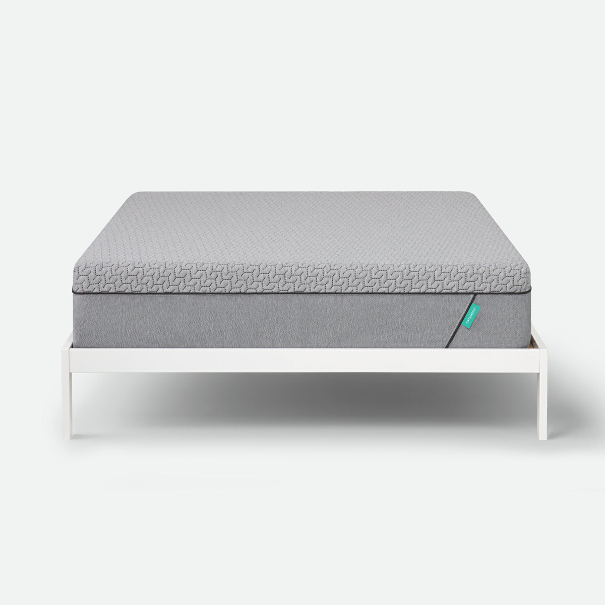 Tuft & Needle Gray mattress on a white bed frame against a white background