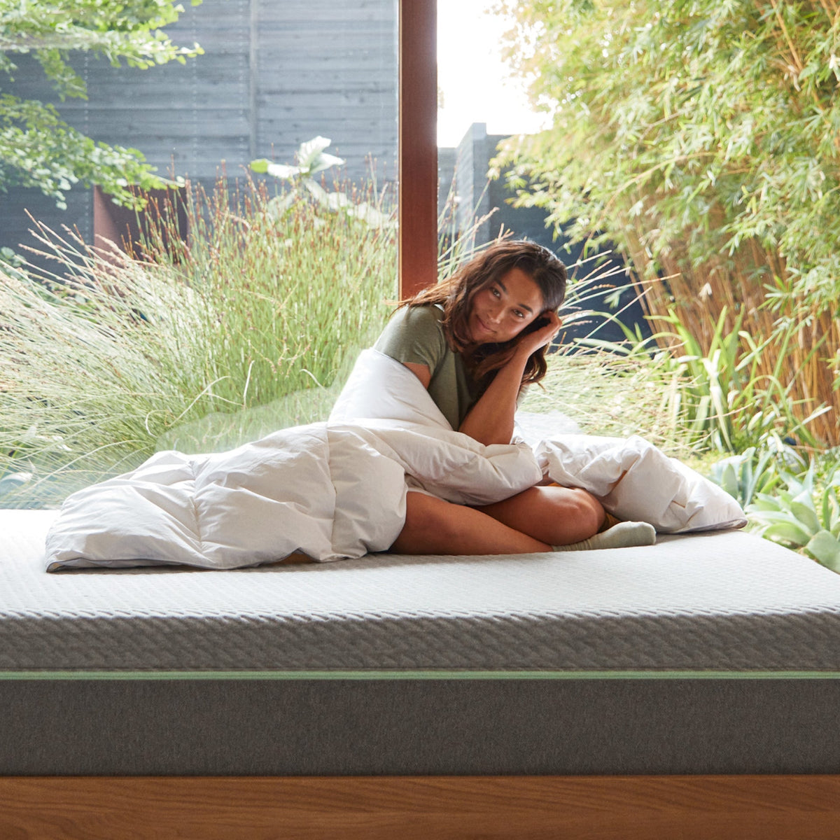 A woman on a bed wrapped in the  Tuft and Needle Down Duvet Insert||weight:light