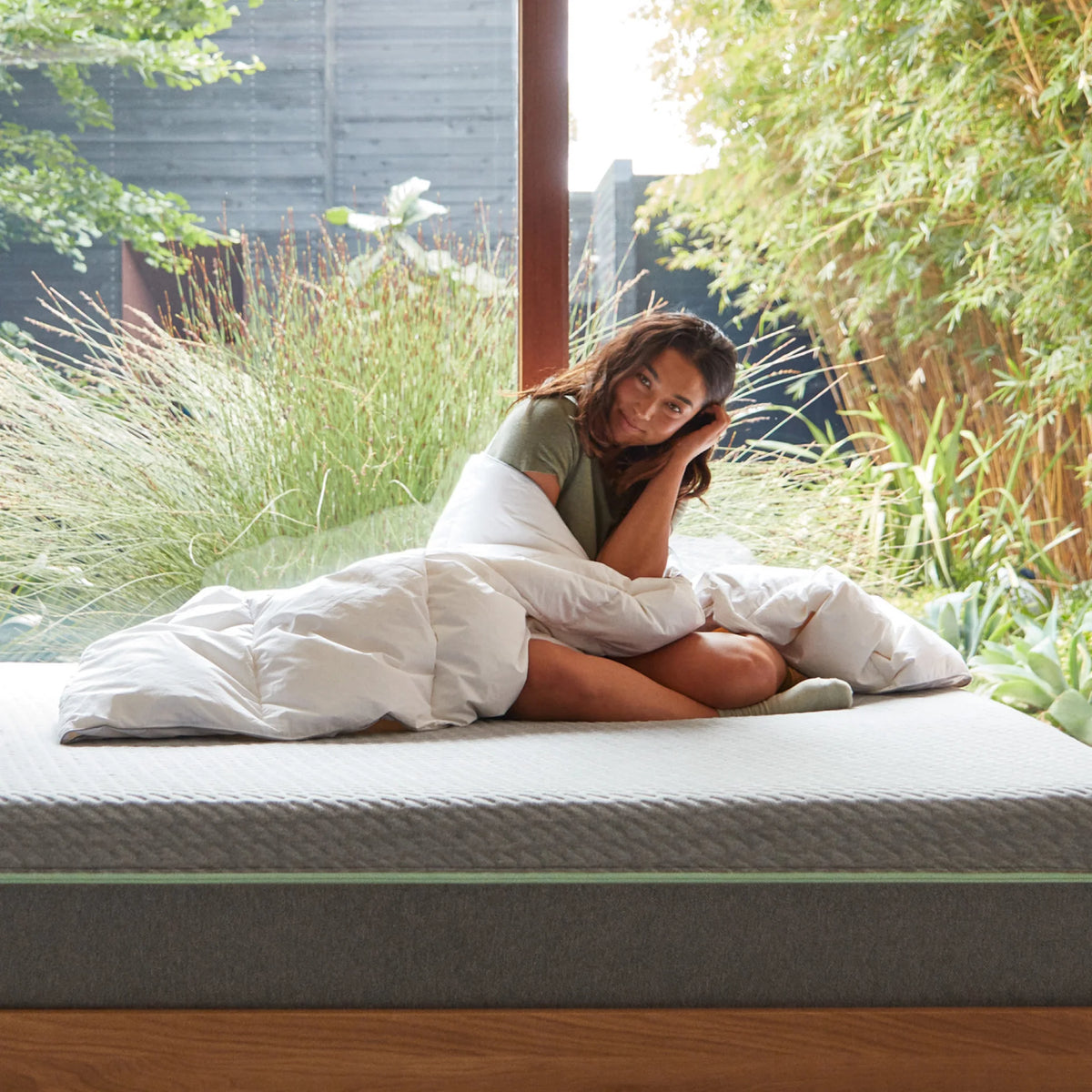 Woman sits on a mattress wrapped in a T&N duvet. 