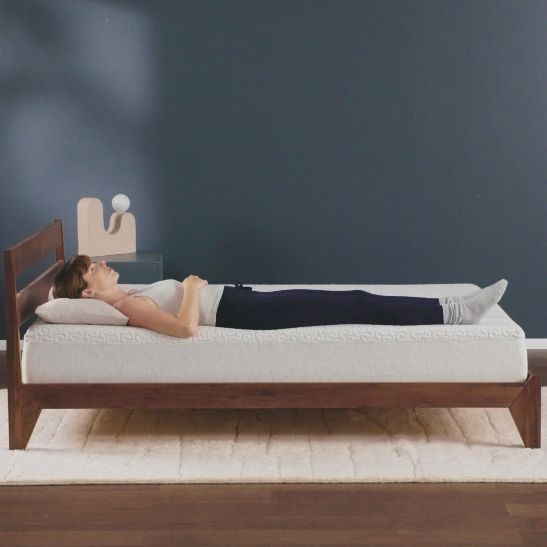 Woman rolls over on her side on a foam mattress. 